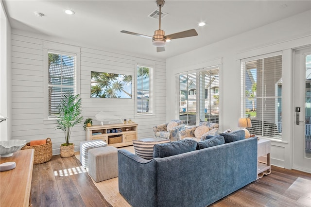 living room featuring wood walls, hardwood / wood-style flooring, and ceiling fan