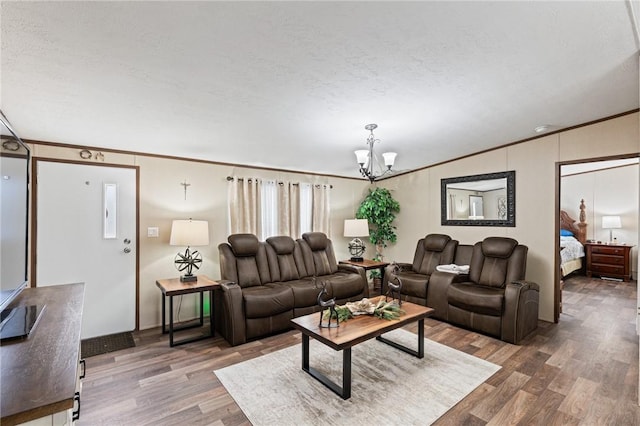 living room featuring crown molding, hardwood / wood-style floors, a chandelier, and a textured ceiling