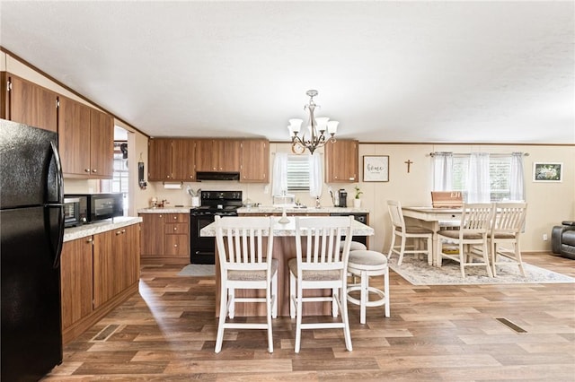 kitchen featuring a chandelier, light hardwood / wood-style flooring, a center island, and black appliances