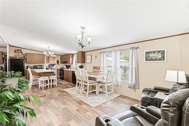 living room featuring a chandelier, vaulted ceiling, and light hardwood / wood-style flooring