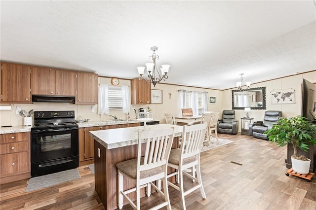 kitchen with black electric range, a center island, hanging light fixtures, and a notable chandelier