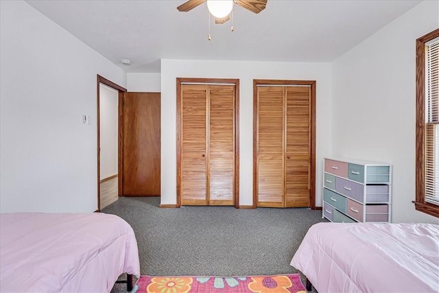 carpeted bedroom featuring ceiling fan and two closets