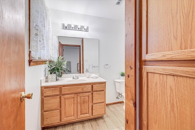 bathroom with wood-type flooring, vanity, and toilet