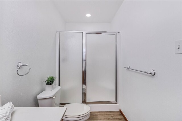 bathroom with walk in shower, hardwood / wood-style floors, and toilet