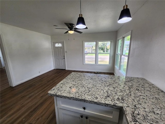 kitchen featuring white cabinetry, ceiling fan, dark wood-type flooring, light stone counters, and decorative light fixtures