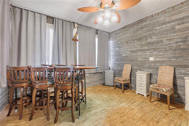 dining space featuring light hardwood / wood-style flooring, ceiling fan, and wood walls