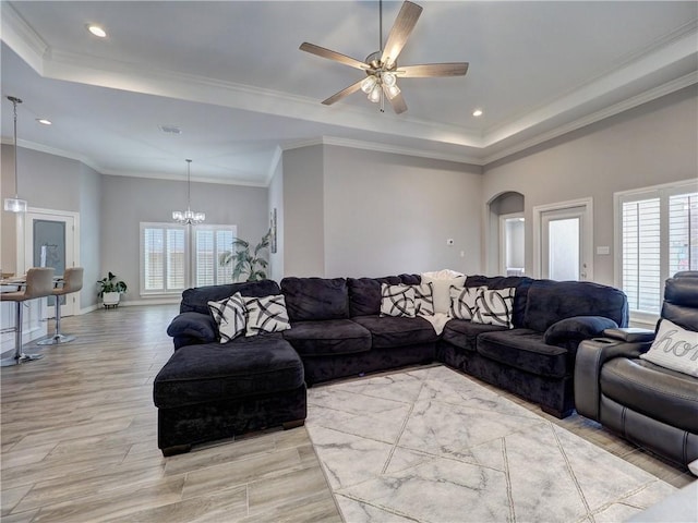 living area with a tray ceiling, a healthy amount of sunlight, and arched walkways