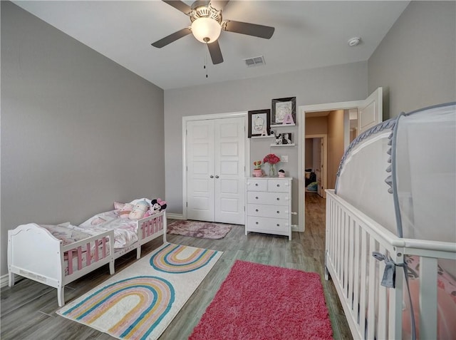 bedroom featuring a ceiling fan, wood finished floors, visible vents, and a closet