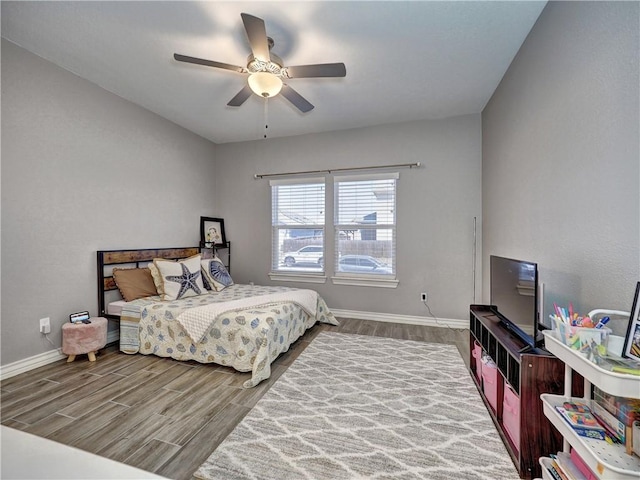 bedroom with a ceiling fan, baseboards, and wood finished floors