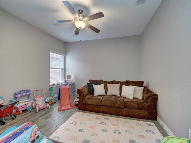 living area with ceiling fan, baseboards, and wood finished floors