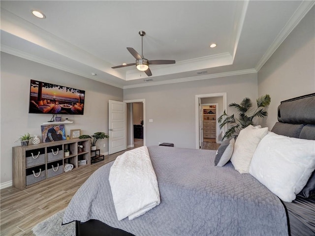 bedroom with a raised ceiling, crown molding, light wood-type flooring, and baseboards