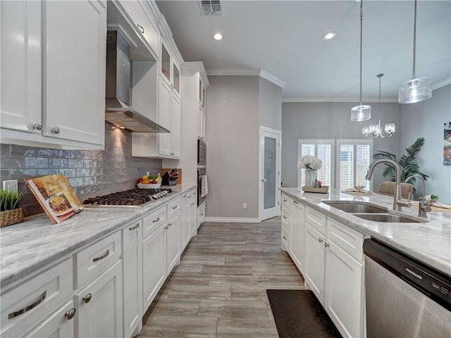 kitchen with visible vents, a sink, tasteful backsplash, appliances with stainless steel finishes, and wall chimney range hood