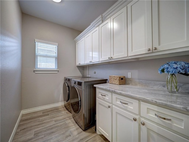 washroom featuring baseboards, cabinet space, washing machine and dryer, and wood tiled floor