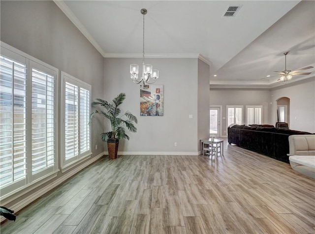 interior space featuring visible vents, baseboards, light wood finished floors, arched walkways, and ornamental molding