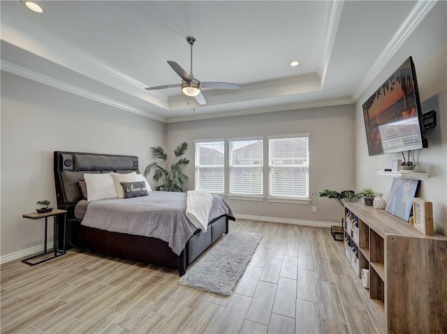 bedroom with baseboards, light wood-type flooring, and a tray ceiling