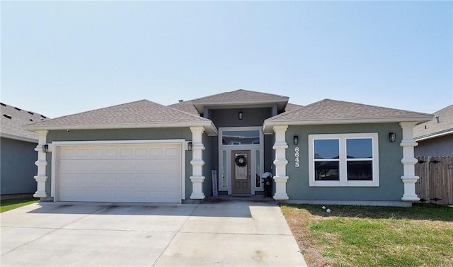 prairie-style home with an attached garage, fence, roof with shingles, stucco siding, and driveway