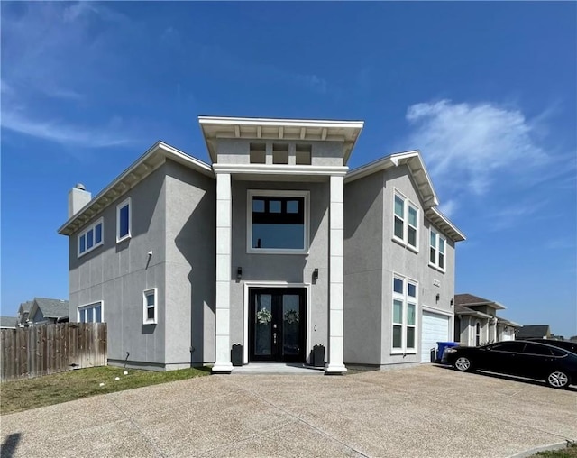 view of front of house with fence, stucco siding, french doors, a chimney, and driveway