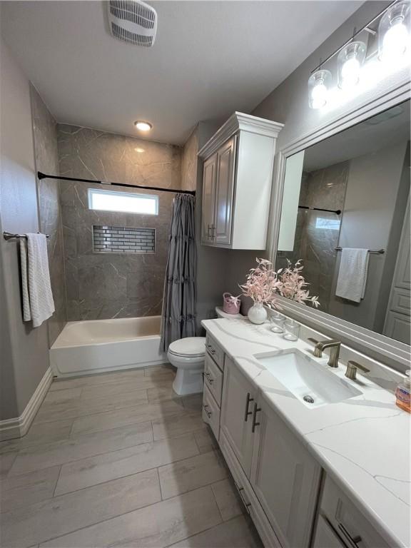 full bathroom featuring visible vents, baseboards, toilet, shower / bath combination with curtain, and vanity