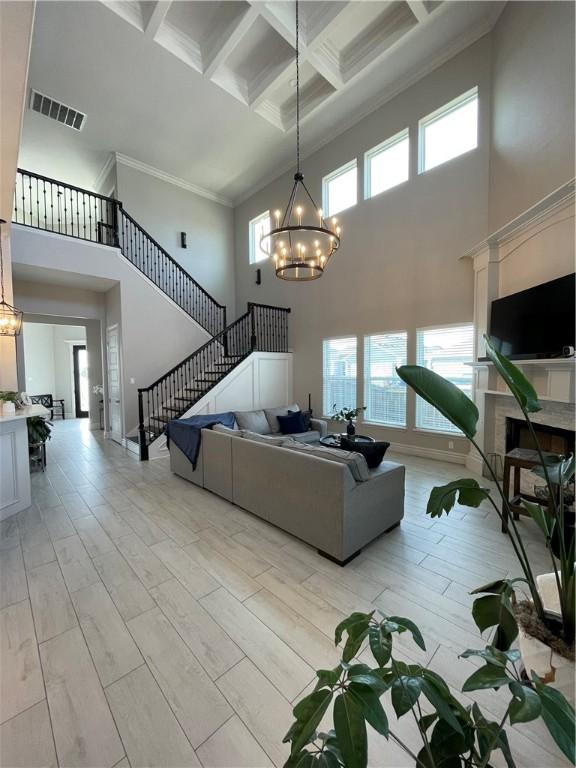 living room with visible vents, coffered ceiling, an inviting chandelier, light wood-style flooring, and beam ceiling