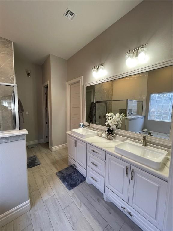 bathroom featuring a shower stall, visible vents, and a sink