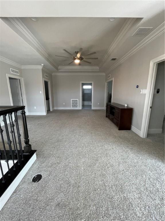 unfurnished living room with a tray ceiling, visible vents, and ceiling fan