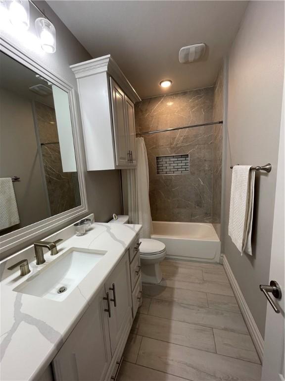 bathroom with vanity, shower / tub combo, toilet, and baseboards