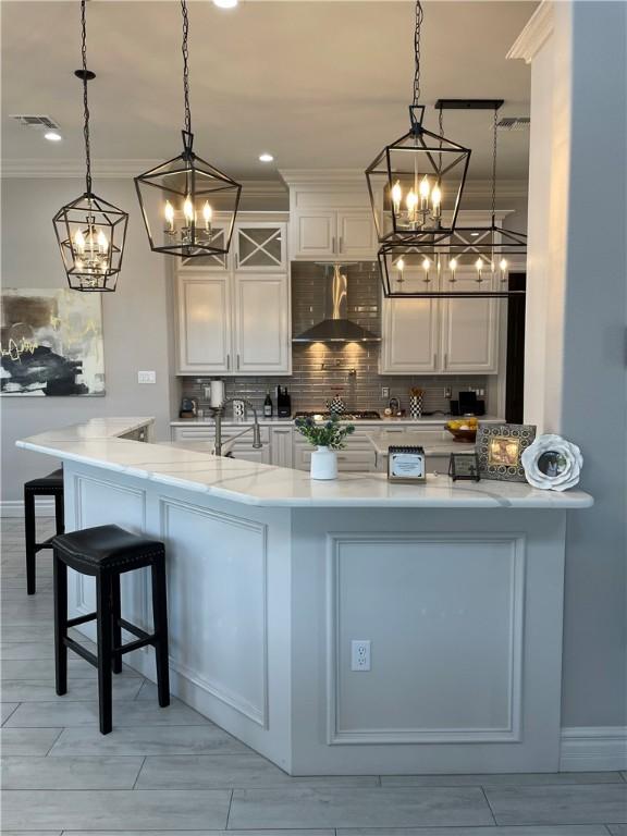 kitchen featuring ventilation hood, decorative backsplash, a notable chandelier, and white cabinets