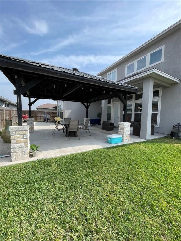 back of property featuring fence, a gazebo, stucco siding, a lawn, and a patio