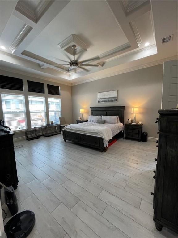 bedroom with a tray ceiling, visible vents, and crown molding