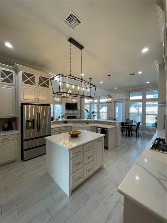 kitchen with visible vents, crown molding, wood finish floors, appliances with stainless steel finishes, and a peninsula