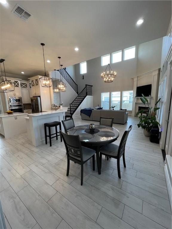 dining area with a chandelier, visible vents, stairway, and a towering ceiling