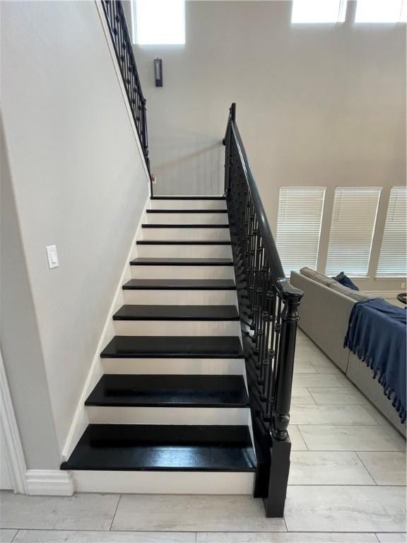 stairway featuring baseboards and a high ceiling