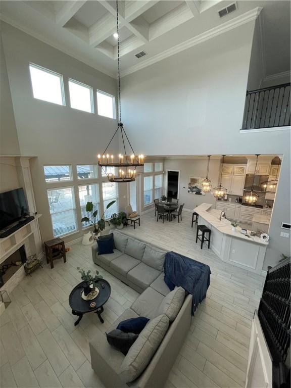 living area with a chandelier, visible vents, a tile fireplace, and a high ceiling