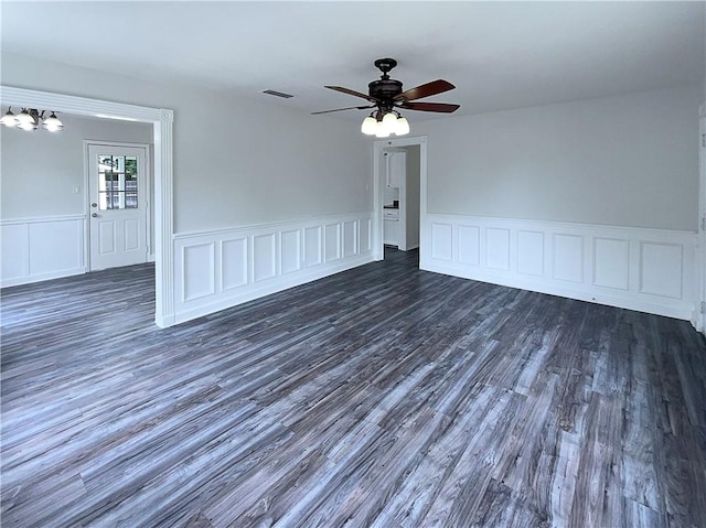 6042 Hugo Dr, Corpus Christi, TX 78412 - unfurnished room featuring dark wood-style floors, a wainscoted wall, ceiling fan, and a decorative wall