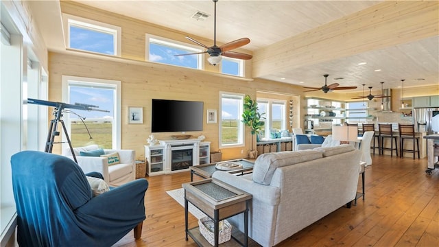 living room with a fireplace, a towering ceiling, hardwood / wood-style flooring, and wooden walls