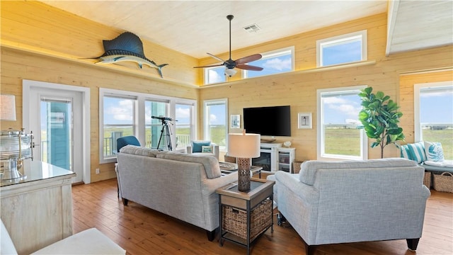 living room featuring wood-type flooring, ceiling fan, and wooden walls