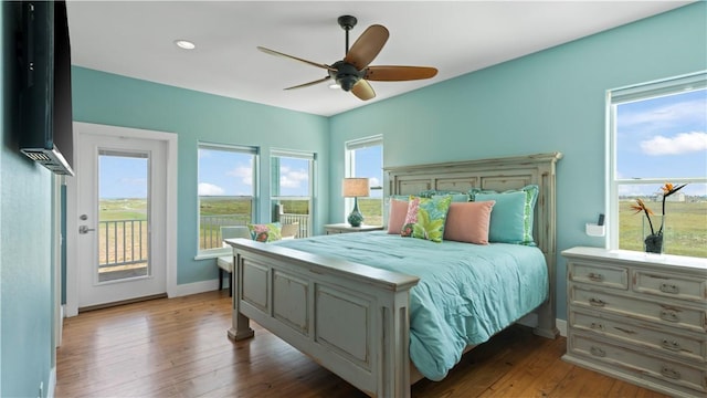 bedroom with access to outside, multiple windows, and hardwood / wood-style flooring