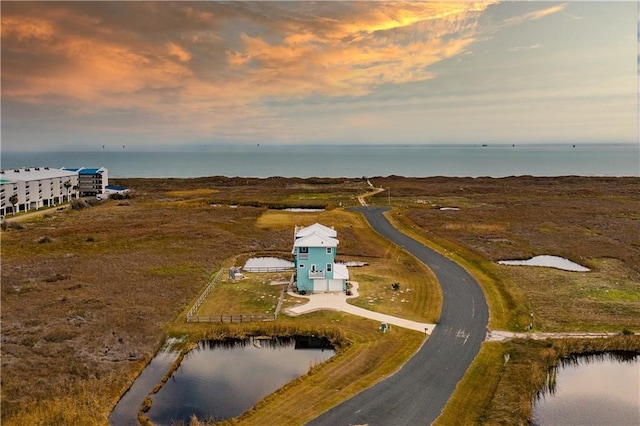 aerial view at dusk featuring a water view