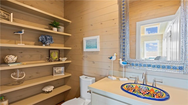 bathroom with wooden walls, vanity, and toilet