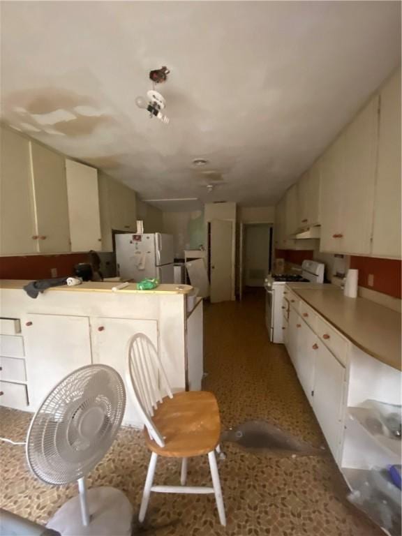 kitchen with lofted ceiling, white appliances, kitchen peninsula, and white cabinets