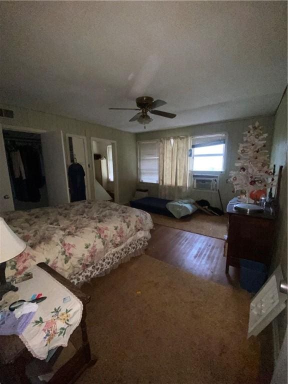 bedroom featuring cooling unit, hardwood / wood-style flooring, a textured ceiling, and ceiling fan