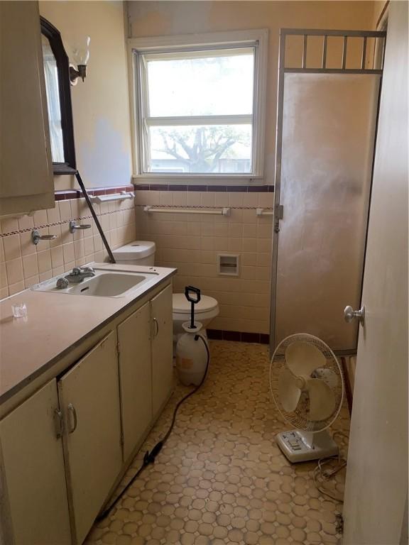 bathroom featuring vanity, toilet, and tile walls