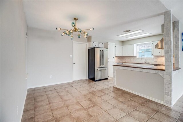 13810 Mizzen St, Corpus Christi, TX 78418 - kitchen featuring high end fridge, a sink, decorative backsplash, a chandelier, and white cabinetry