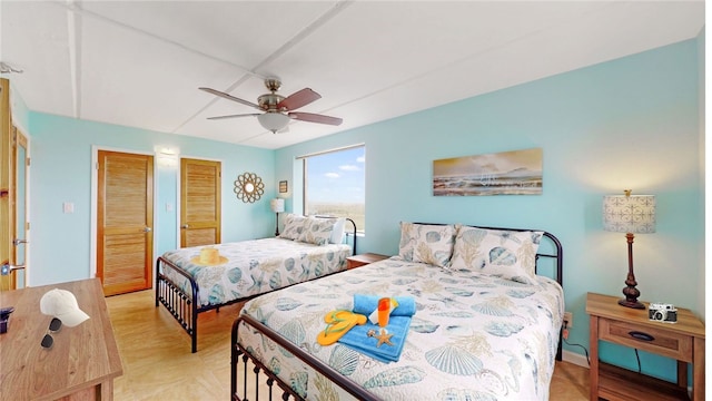 bedroom featuring ceiling fan, multiple closets, and light hardwood / wood-style flooring