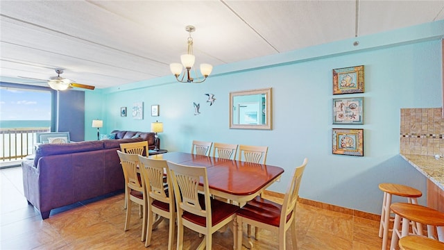 dining space with a water view and ceiling fan with notable chandelier