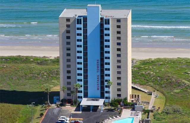 view of building exterior featuring a water view and a beach view