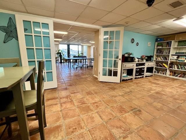 interior space with a drop ceiling and french doors