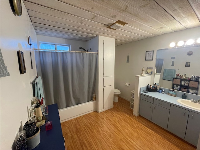 full bathroom featuring hardwood / wood-style floors, vanity, shower / bath combination with curtain, and toilet