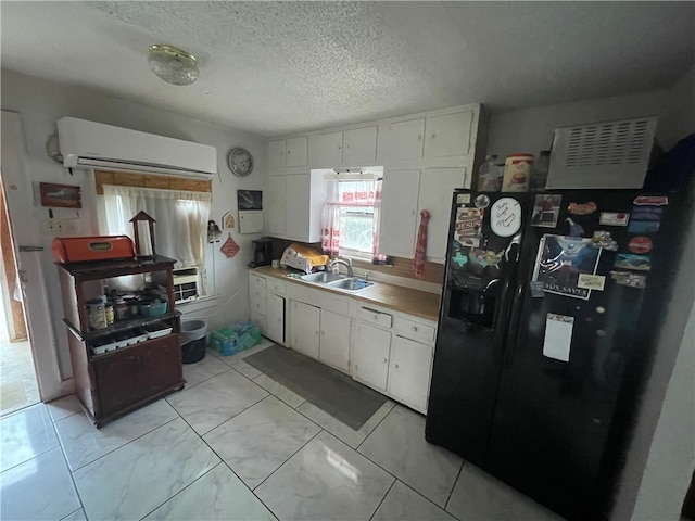 kitchen featuring black refrigerator with ice dispenser, sink, a textured ceiling, a wall mounted AC, and white cabinetry