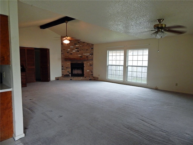 unfurnished living room with ceiling fan, lofted ceiling with beams, a textured ceiling, light carpet, and a fireplace